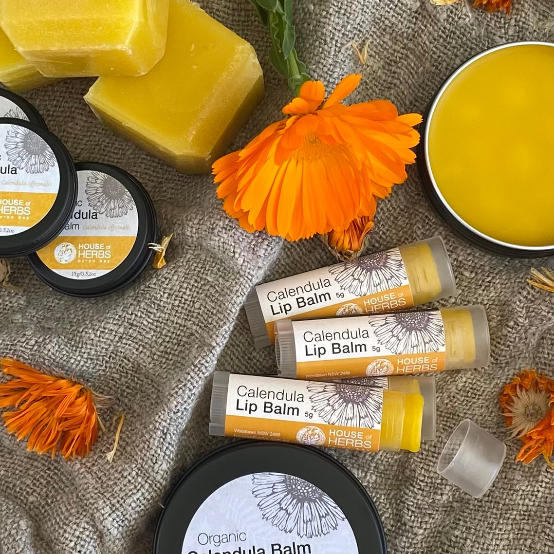 Organic calendula lip balm with manuka bees wax and organic calendula flowers on a raw linen background