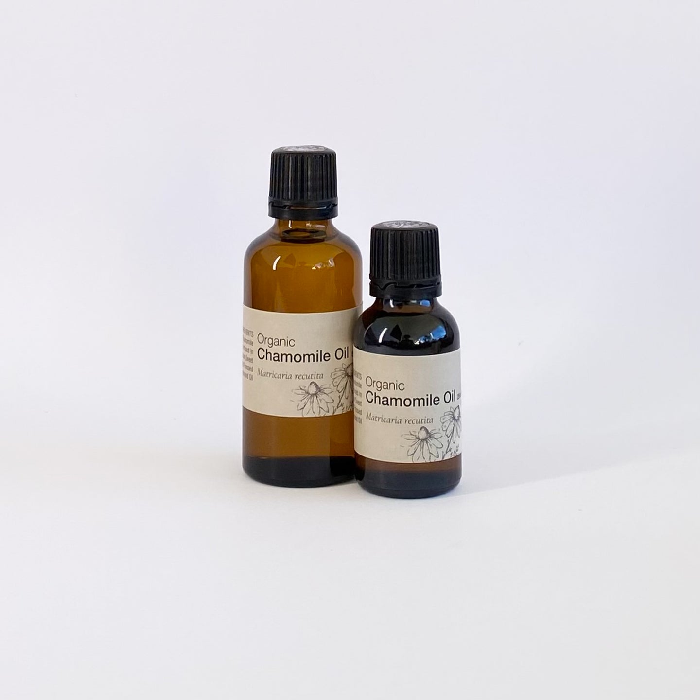 Two bottles of organic chamomile oil on a white background
