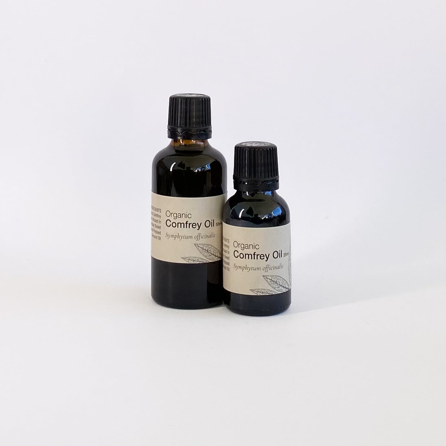 Two bottles of organic comfrey oil on a white background