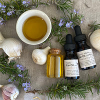 Herbal remedies with garlic bulbs, oil, and bottles on a textured surface.