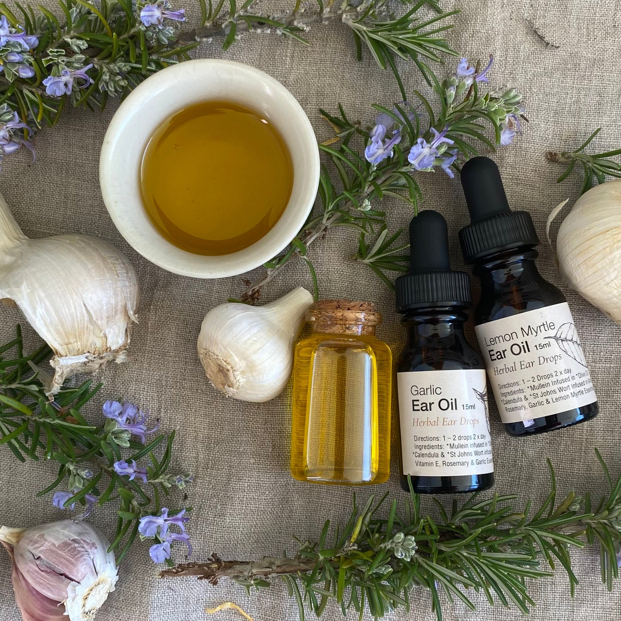 Herbal remedies with garlic bulbs, oil, and bottles on a textured surface.