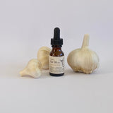 Bottle of Garlic Ear Oil with garlic bulbs on a white background