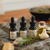 Three bottles of ear oil on a textured surface with a blurred background
