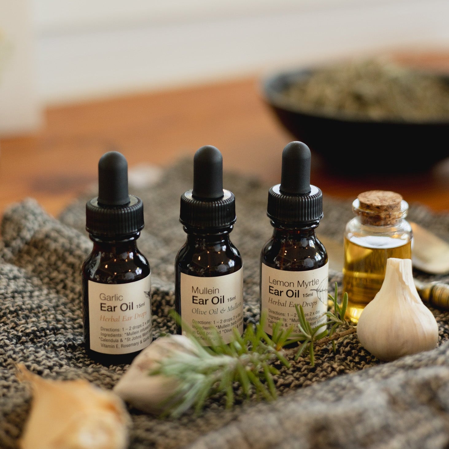 Three bottles of ear oil on a textured surface with a blurred background