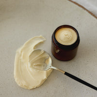 Jar of cream with a spoonful on a textured surface