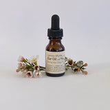 Bottle of Lemon Myrtle Ear Oil with a dropper on a white background with flowers.