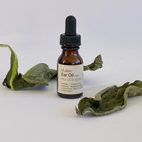 Bottle of Mullein Ear Oil with dried mullein leaves on a white background