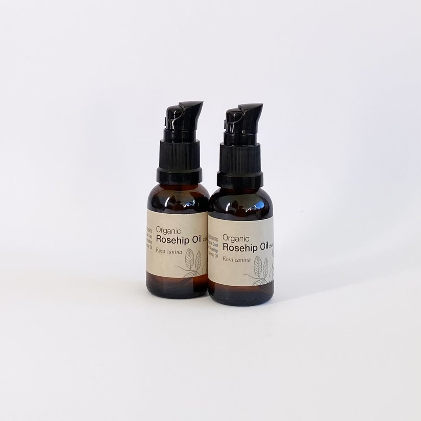 Two bottles of Organic Rosehip Oil on a white background